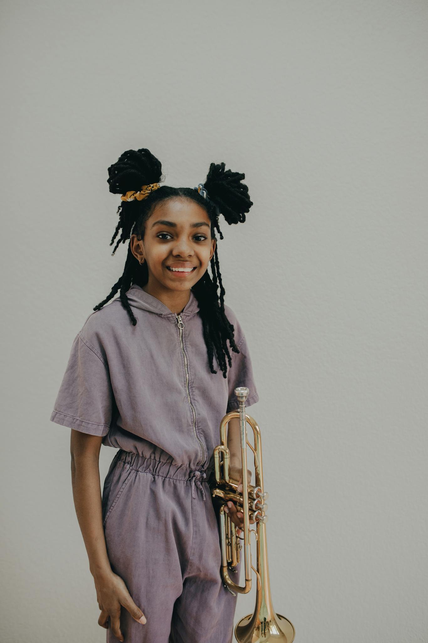 Young girl with trumpet, smiling confidently in casual wear.